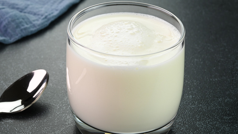 A glass of buttermilk sitting on a black countertop