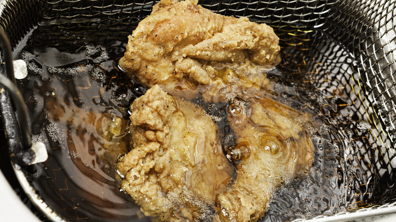 Chicken frying in a mesh basket