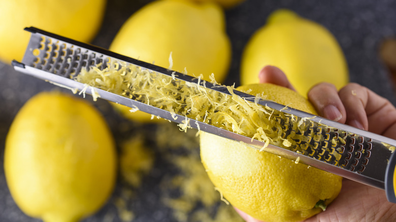 A hand zesting a lemon with a grater