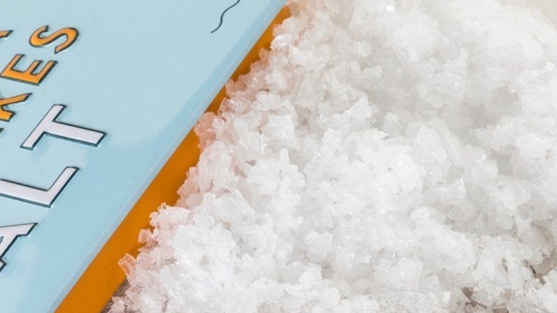 A close-up of sea salt flakes next to packaging