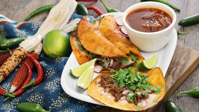 Birria tacos on a plate with consomme