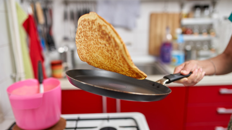 woman's hand flipping large pancake