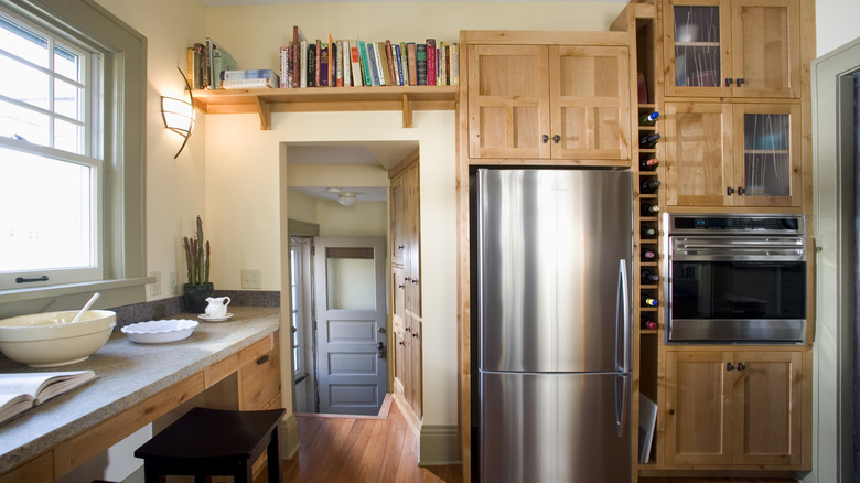 A silver refrigerator sits in a cozy kitchen with wood cabinets.