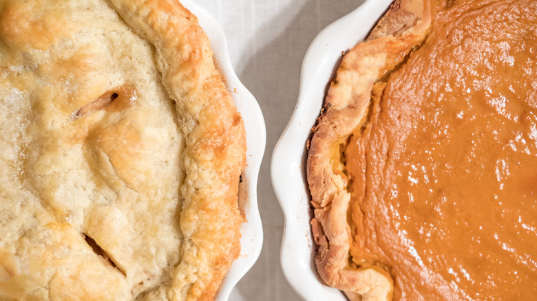 A pumpkin pie sits next to a pie with a top crust.