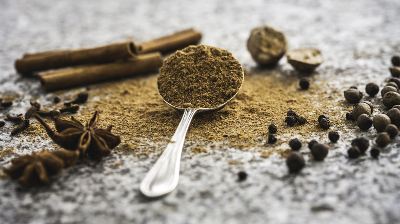 Ingredients for pumpkin spice mix are on table and on a spoon.