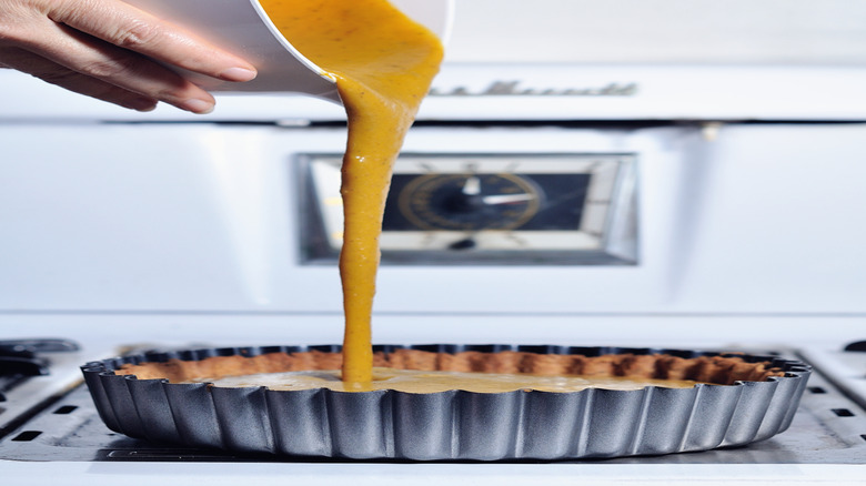 A stream of pumpkin pie filling is pouring out of a bowl.