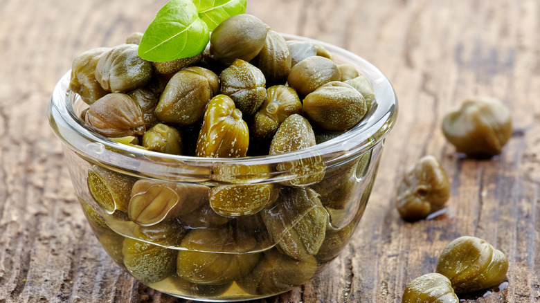 A bowl of capers on a wooden table