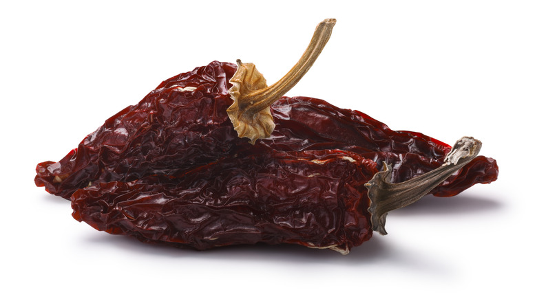 Three dried chipotle chiles against a white background