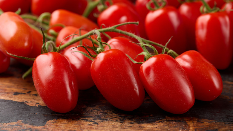 A bunch of San Marzano tomatoes on the vine on a wooden table