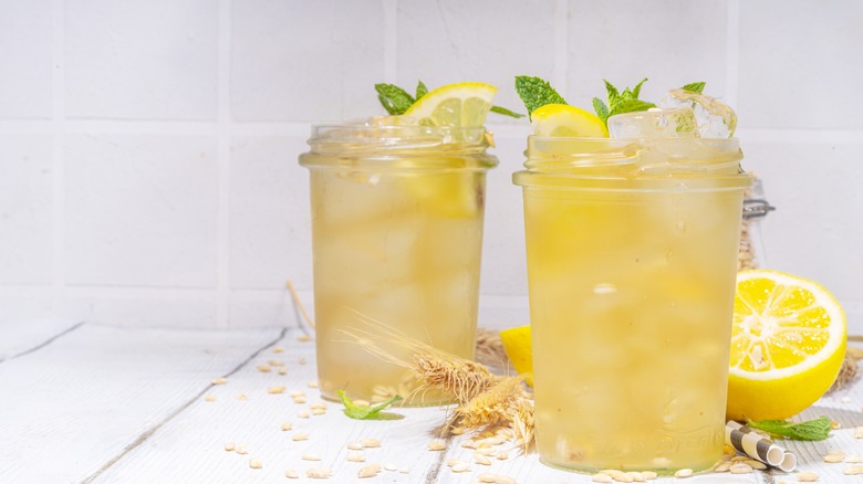 Two glasses of barley lemonade sit on a table.