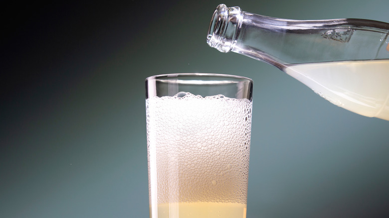 Bottle pours liquid into a glass.
