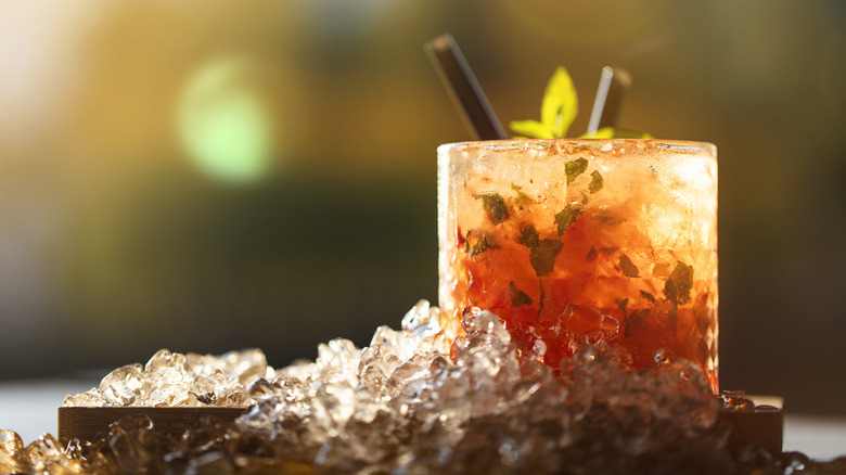 Orange cocktail sits atop a pile of ice.