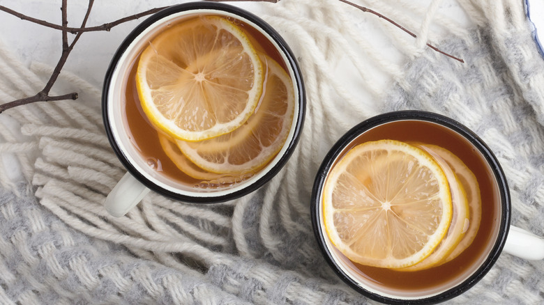 Lemon slices float in glasses of dark tea.