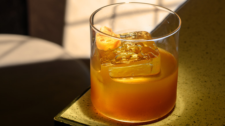 Cloudy brown cocktail sits on a table.