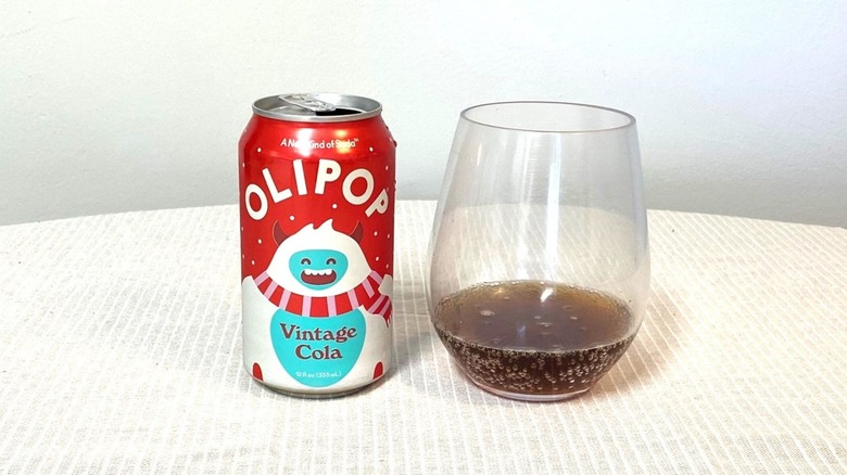 a glass of Olipop Vintage Cola on a table beside its colorful can