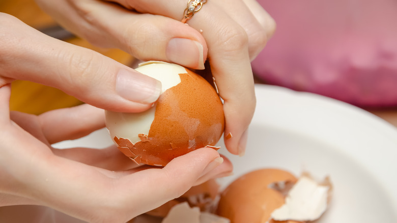 hands peeling brown egg