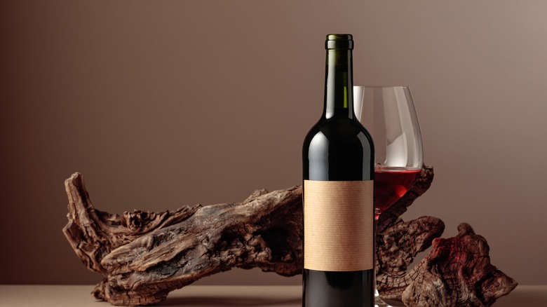 red wine bottle and glass next to bark