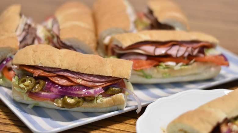 A blue and white tray with six Subway sandwiches on a wooden table