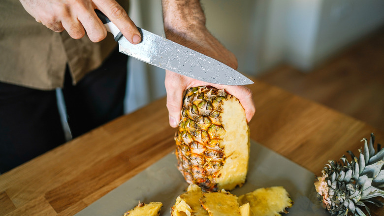 man cutting a pineapple