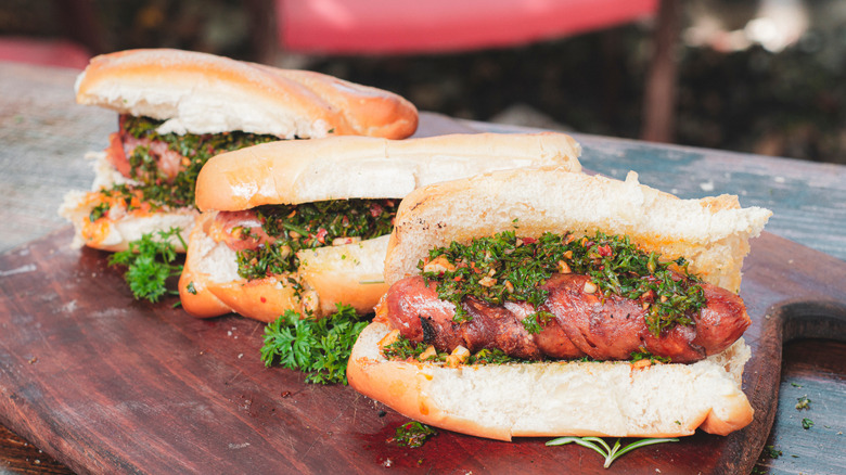 Three hot dogs topped with chimichurri