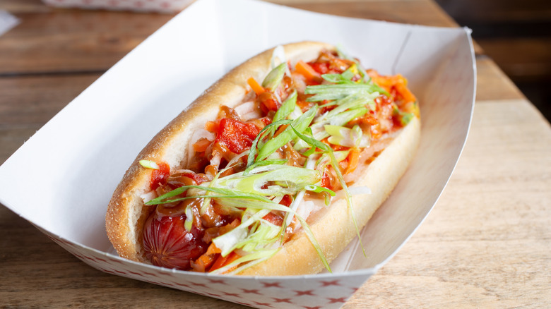 hot dog topped with kimchi and scallions