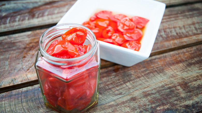 A jar of Peppadew peppers next to a bowl of Peppadew peppers