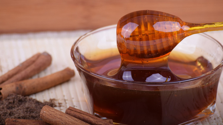 Bowl of honey with cinnamon sticks on the side