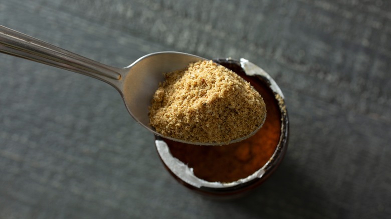 Beef bouillon being scooped in spoon from jar