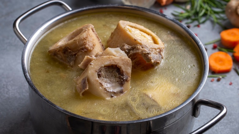 Beef bone broth simmering in a silver pot with whole bones