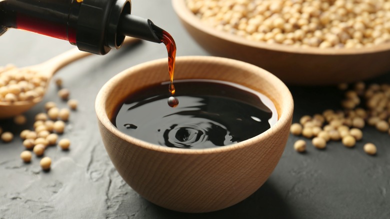 Pouring soy sauce into a wooden bowl