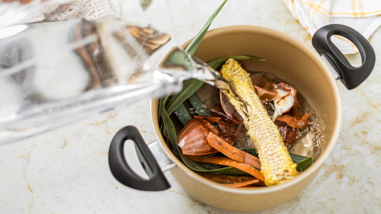 Pouring water into pot of vegetables to make broth