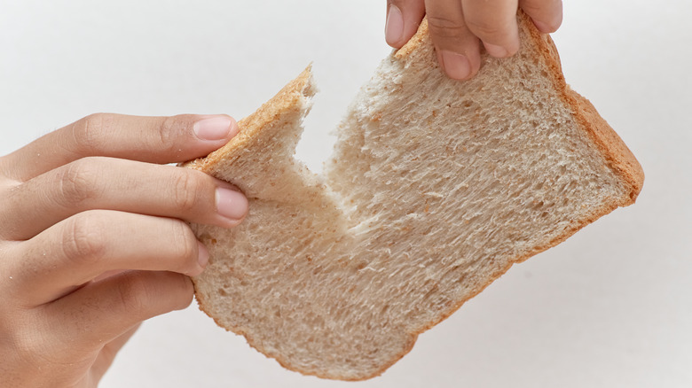 hands breaking a slice of bread