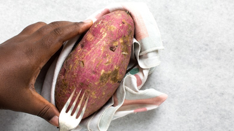 Poking holes in a raw sweet potato