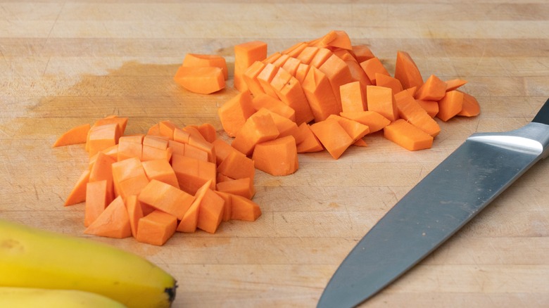 Diced sweet potatoes on a cutting board with a knife