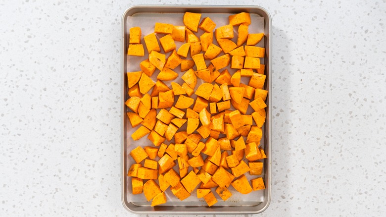 An overcrowded baking sheet of sweet potatoes