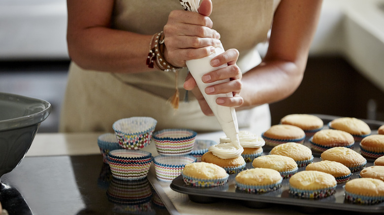 Person icing cupcakes