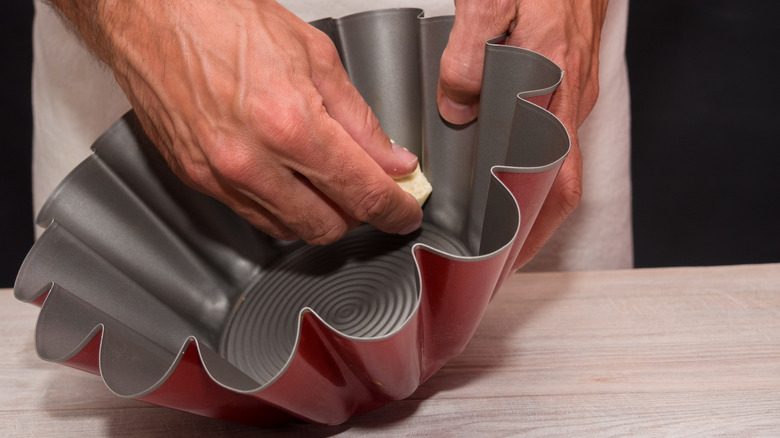 Hands greasing cake mold with butter