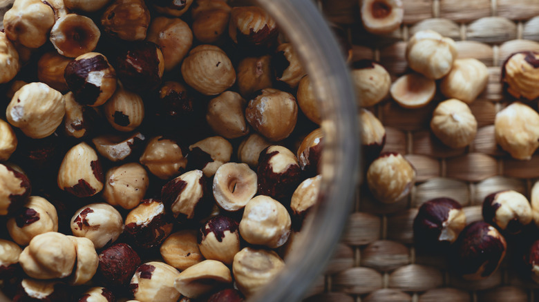 bowl of hazelnuts with a few scattered on table