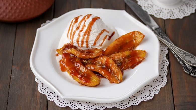 Bananas Foster on a white plate with a scoop of vanilla ice cream drizzled with sauce