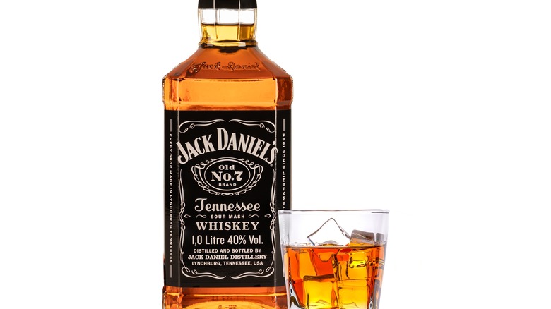 A bottle of Jack Daniels whiskey next to a glass with ice