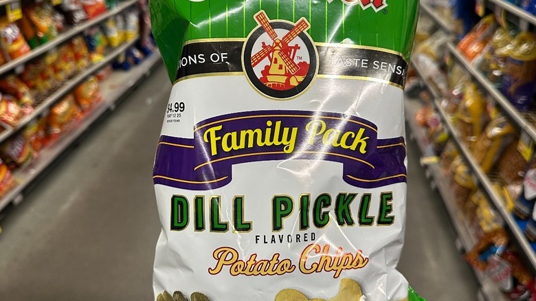 Hand holding Old Dutch dill pickle chips in grocery store aisle