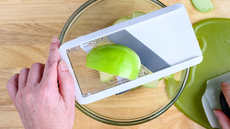 hand holding mandoline slicer over bowl