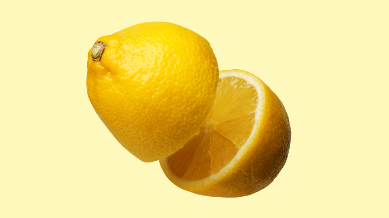 floating lemon cut in half on light yellow background