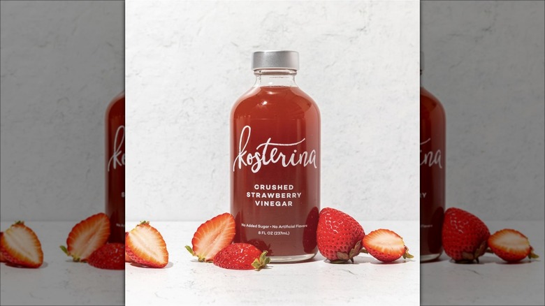 A bottle of Kosterina Crushed Strawberry Vinegar next to strawberries