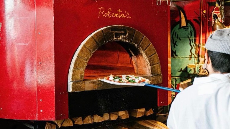 Pizzaiolo putting pizza into Roberta's oven