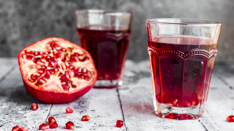 pomegranate juice with cut pomegranate in background