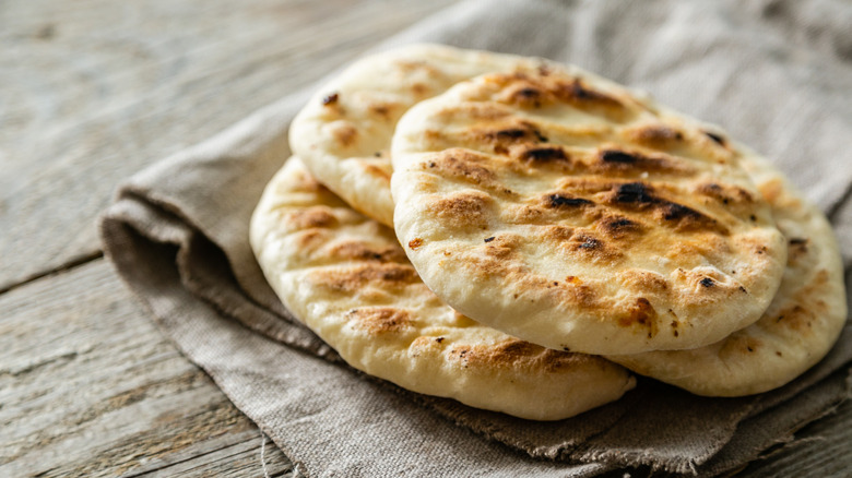 traditional pita breads piled on towel on wooden background