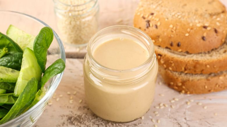 jar of tahini with cucumbers and bread