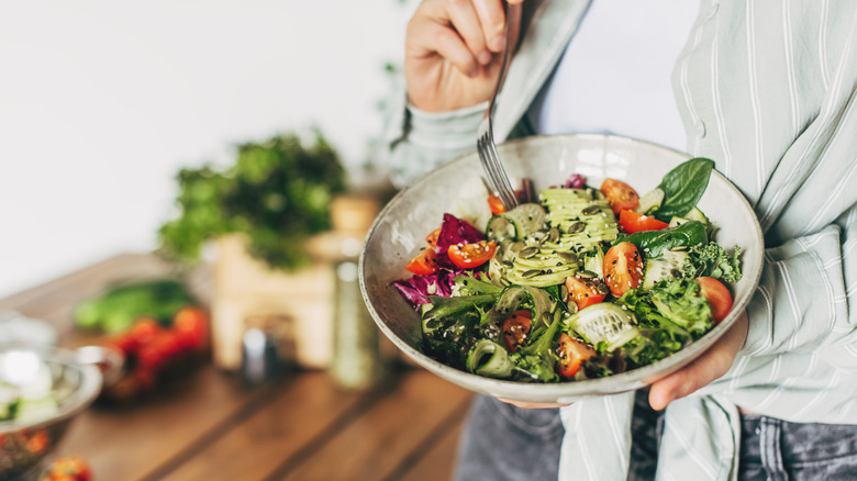 A person pierces a brightly colored salad with a fork.