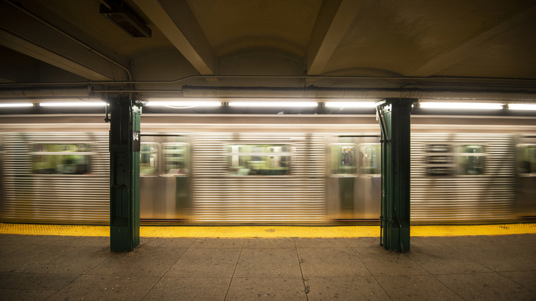 NYC subway stop with subway cars passing by blurrily